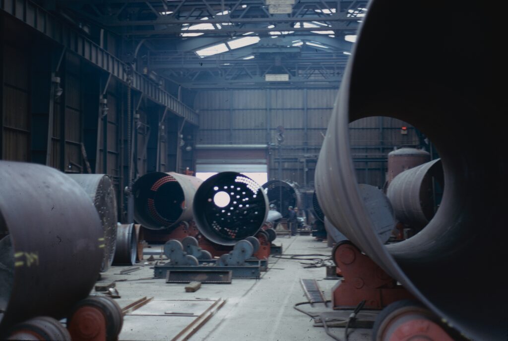 Inside a large warehouse floor with large concrete, metal and other large-scale assembly assets