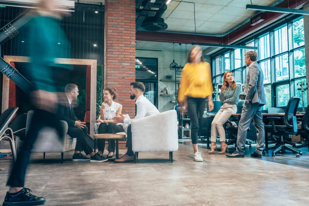 People sit in a group discussion while people walk around them