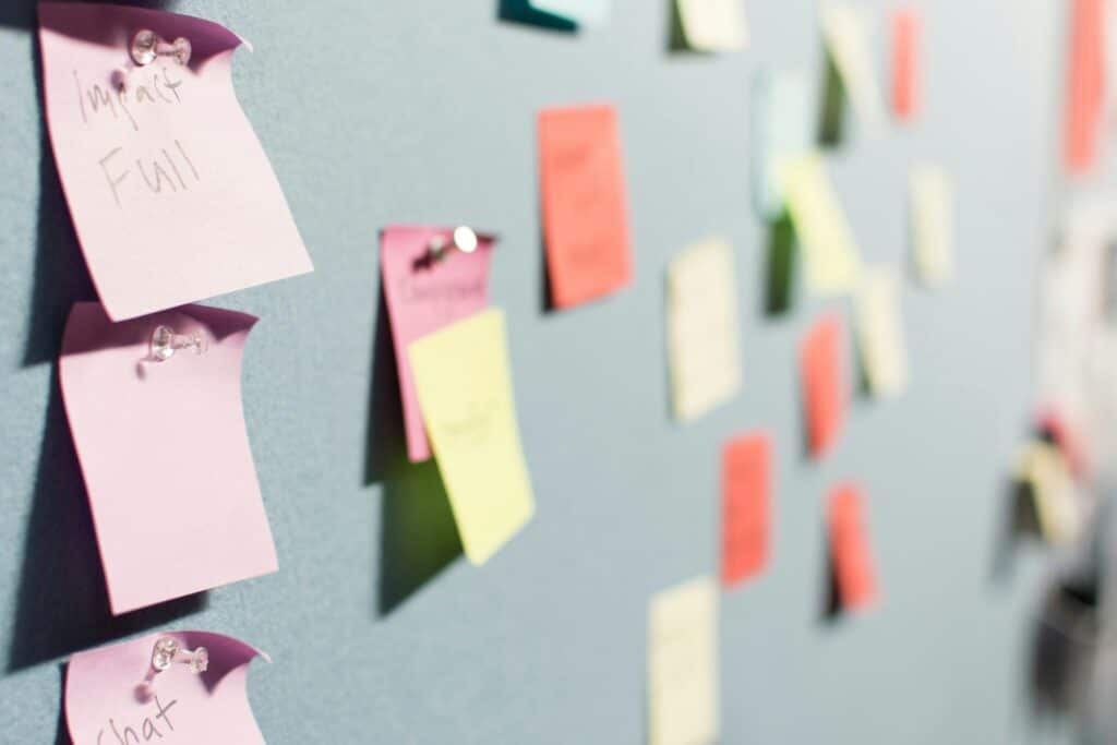 A blue board with yellow, orange and pink sticky notes