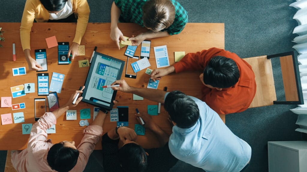 Overhead view of table of people focused on a screen at centre